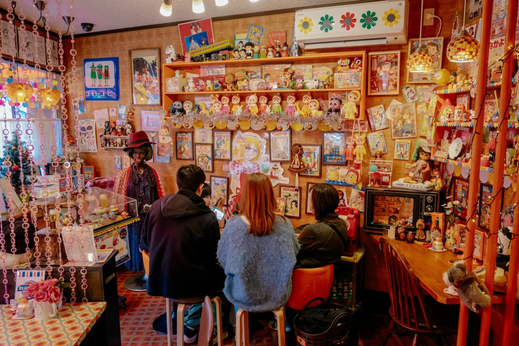 Clienti seduti al bancone del Cafè Sepia a Shibamata, un kissaten celebre per la sua incredibile collezione di giocattoli e memorabilia giapponesi anni '60 e '70.