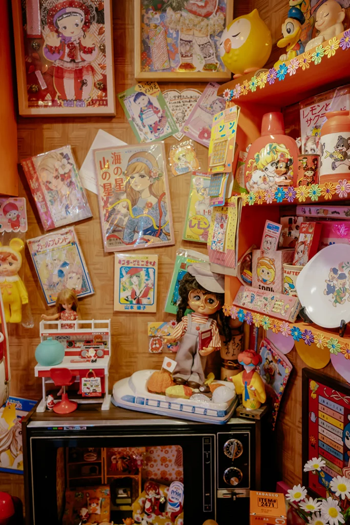 Scaffali colmi di illustrazioni rétro e vecchi giocattoli all'interno del Cafè Sepia a Shibamata, un esempio perfetto di conservazione dell'estetica Shōwa Retro.