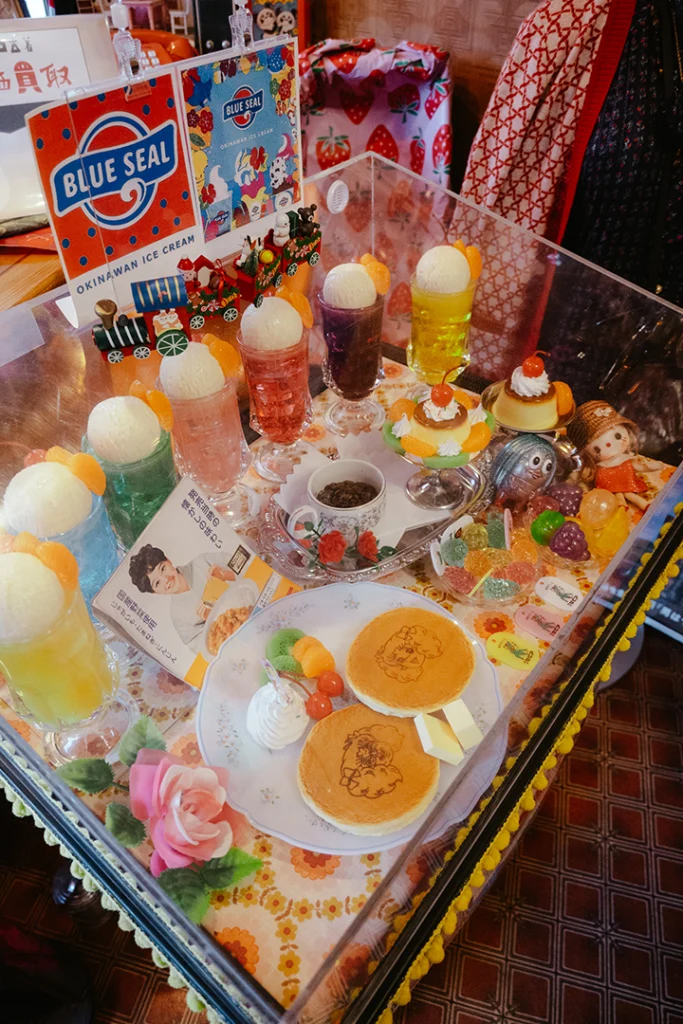 Vetrina di campioni di cibo in cera (sampuru) del Cafè Sepia a Shibamata, che espone pancake decorati, cream soda e parfait in stile Shōwa Retro.