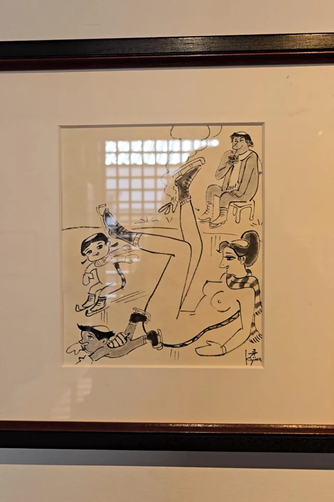 Un disegno in bianco e nero incorniciato del fumettista Koh Kojima che mostra figure di kappa, tra cui una kappa femmina e piccoli kappa che pattinano sul ghiaccio.