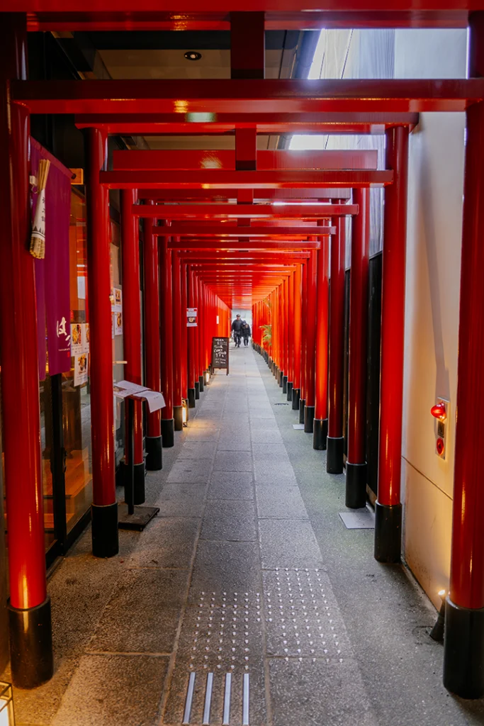 Un lungo tunnel coperto formato da torii rossi tradizionali che decora l'ingresso di un ristorante lungo Nayamachi Shopping Street a Fushimi.